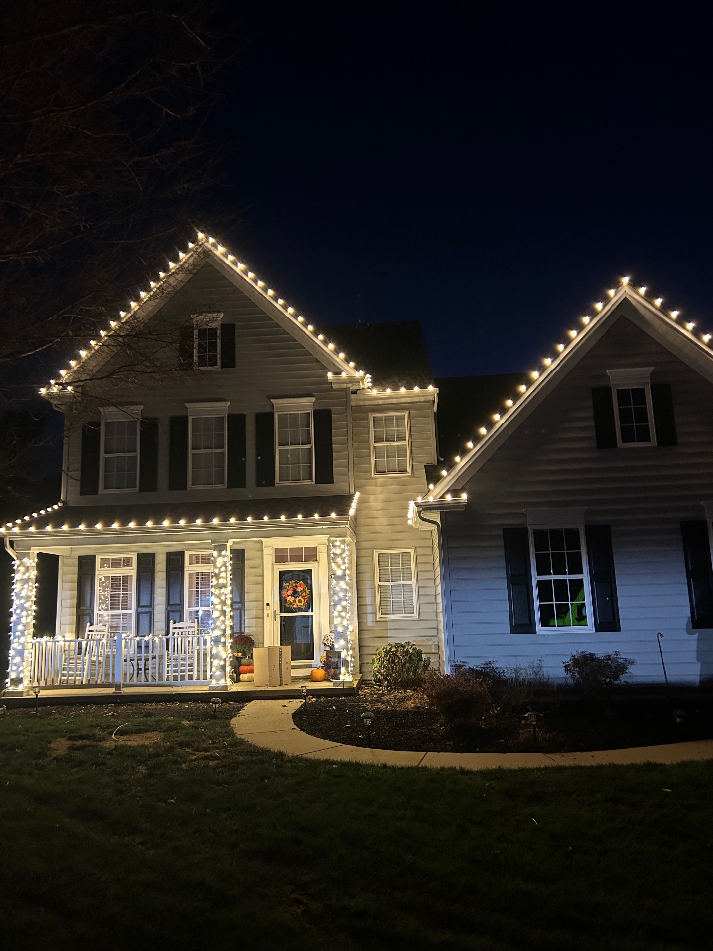 Two-story home in York PA outlined with warm white Christmas lights at night